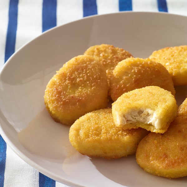 Bocconcini impanati croccanti, uno morso, succosi all'interno.