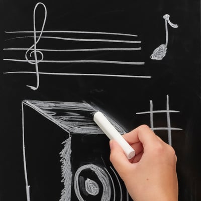 Scrive a mano le note musicali sulla lavagna; un'attività creativa ed educativa.