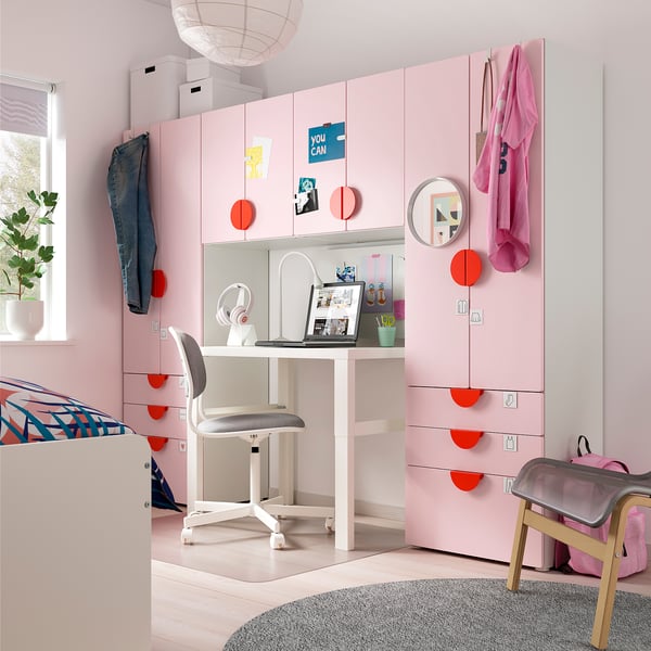 Cameretta rosa brillante con mobili SMÅSTAD, scrivania bianca, sedia da ufficio grigia e decorazioni colorate.