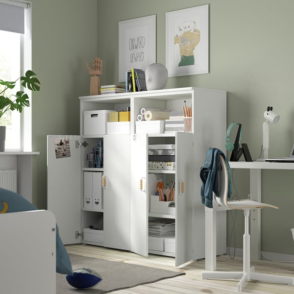 Home office con mobile contenitore bianco. Parete verde, scrivania, sedia e decorazioni.