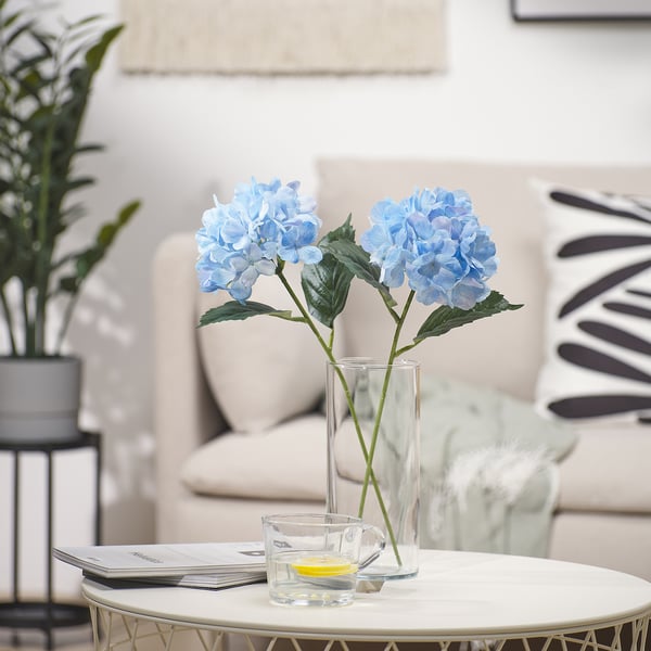 SMYCKA fiori blu in vaso di vetro su tavolino con tazze, vicino al divano e alla pianta.