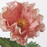 primo piano di papavero artificiale vibrante e realistico; petali morbidi, centro luminoso, foglie verdi.