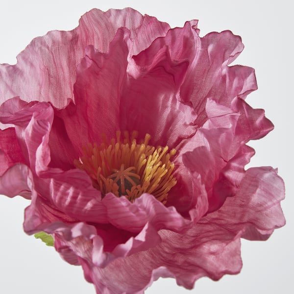 Fiore artificiale realistico con petali rosa vivaci e centro arancione, realizzato con materiali riciclati.