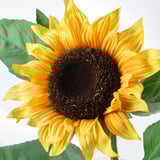 Girasole giallo brillante con foglie verdi, meticolosamente realizzato per assomigliare a veri petali e stelo, che trasuda qualità realistica.