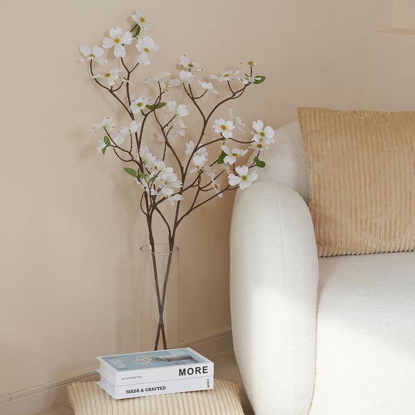 Vaso con fiori artificiali bianchi accanto alla sedia e ai libri.