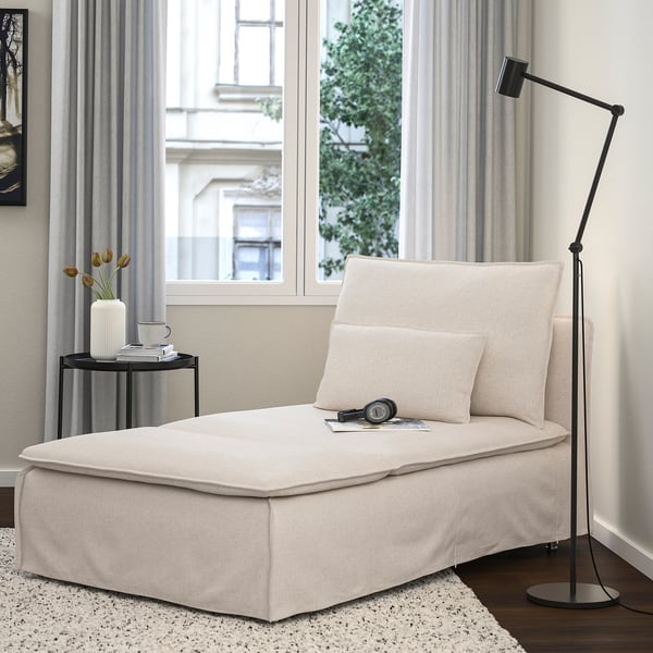 Chaise longue SÖDERHAMN color gesso con cuscino, accanto al tavolino nero con tulipani e lampada da terra, su tappeto.