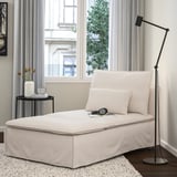 Chaise longue SÖDERHAMN color gesso con cuscino, accanto al tavolino nero con tulipani e lampada da terra, su tappeto.