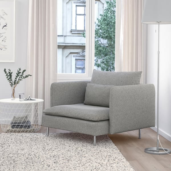 Sedia SÖDERHAMN, grigia, accogliente con tessuto strutturato, compatta per piccoli spazi, gambe in legno, vicino a una grande finestra, morbidi cuscini.