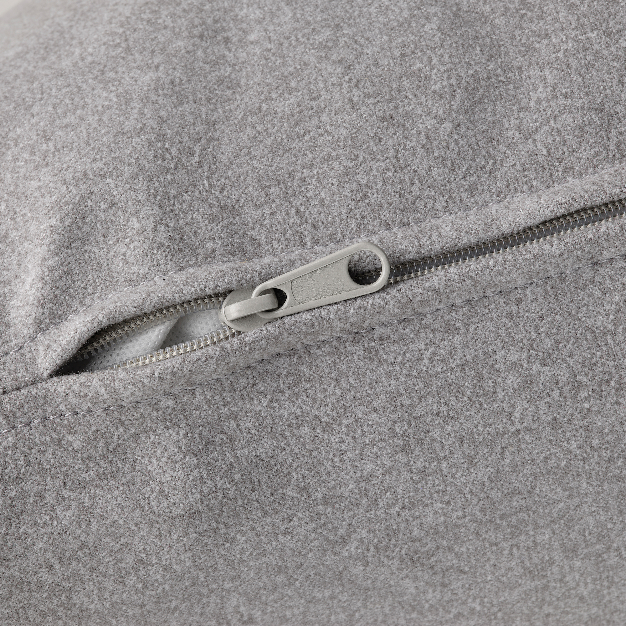 Primo piano di una cerniera grigia su tessuto morbido e di alta qualità.