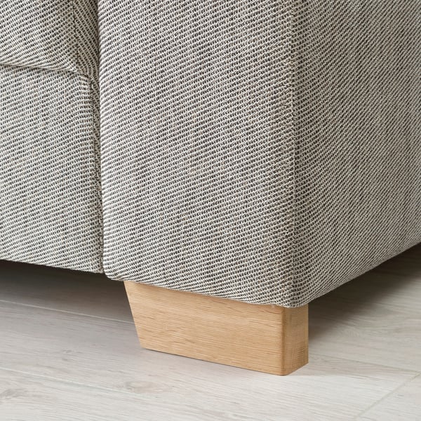 Primo piano della base del divano moderno, tessuto grigio chiaro con motivo intricato, sostenuto da un robusto blocco di legno chiaro.