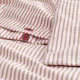Camicia a righe con colletto button-down. Il primo piano mostra i dettagli del pulsante rosso.