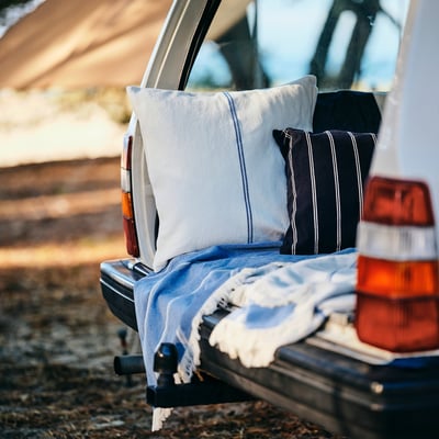 I veicoli sono al retro con due cuscini a strisce, copertura morbida in cotone, texture di juta, coperta grigia e luci posteriori.