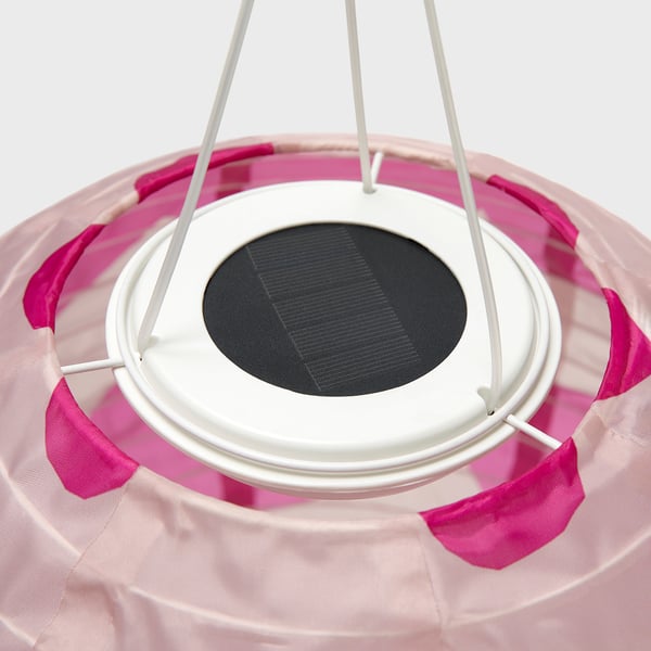 Lampada a sospensione a energia solare con strisce di tessuto rosa, cornice bianca e pannello solare centrale.