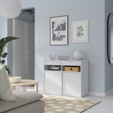 Soggiorno moderno e minimalista con credenza SPIKSMED bianca, contenitore versatile, parete grigia, arte, specchio e divano.