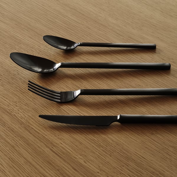 Quattro posate moderne posate ordinatamente posate su una superficie di legno. Finitura in acciaio inossidabile scuro, design elegante.