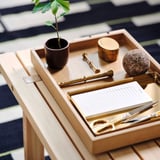 Vassoio STOCKHOLM 2025 con forbici d'oro, quaderno, pianta e candela. Legno di quercia, rettangolare, design scandinavo minimalista.