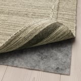 Un tappeto grigio con feltro antiscivolo sottostante, che impedisce lo scivolamento e i graffi del pavimento.