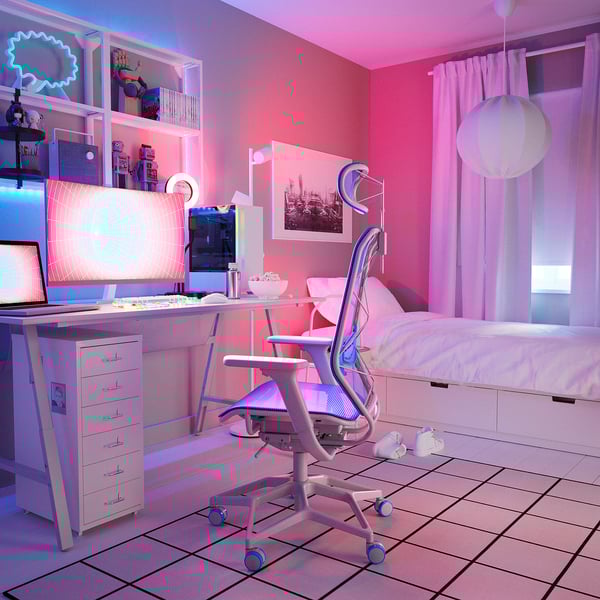 Camera da letto illuminata al neon con scrivania, sedia e letto bianchi. Computer, decorazioni e luci vivaci.