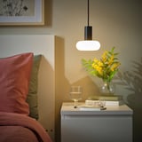 Accogliente angolo camera da letto con lampada SUNNEBY, libri, fiori e cuscini caldi.