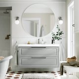 Mobile da bagno grigio con specchio, luci e piante.