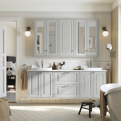 Spazioso mobile da bagno grigio con doppi lavandini, circondato da armadi a specchio e lampade da parete.