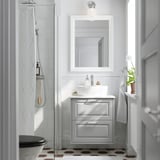 Bagno moderno con lavabo bianco TÄNNFORSEN, lavabo, specchio a parete, doccia in vetro, piastrelle a motivi geometrici e pianta in vaso.