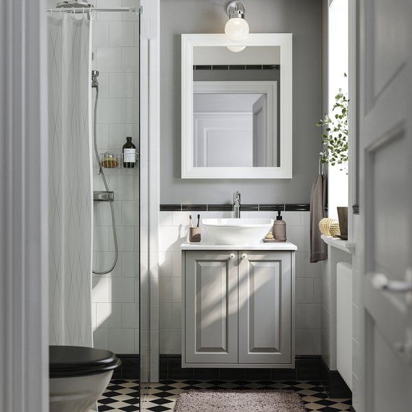 Un bagno moderno con armadietto bianco TÄNNFORSEN, elegante lavandino, specchio e doccia in vetro.