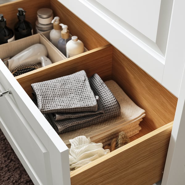Cassetto del bagno in legno aperto con asciugamani e articoli da toeletta ben piegati, che mostrano lo spazio organizzato.