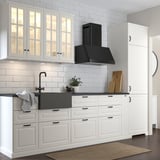 Cucina moderna con armadi bianchi, lavello in quarzo grigio scuro, rubinetto nero e cappa nera. Il lavandino è grande, profondo e di forma quadrata.