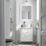 Bagno bianco moderno: pavimento piastrellato esagonale, lavandino in marmo, asciugamani appesi, doccia in vetro, specchio, lampadina singola.