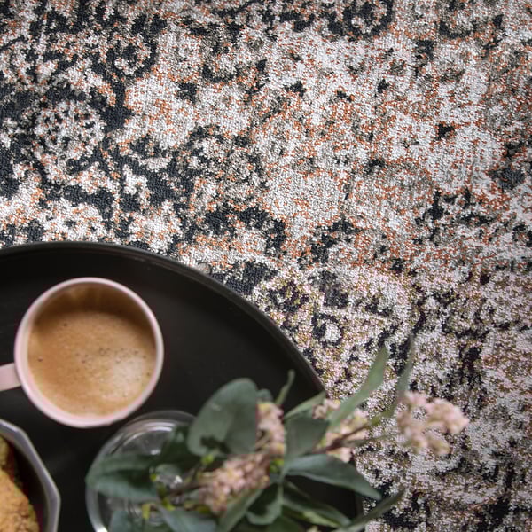 Una scena accogliente con una tazza di caffè e fiori freschi su un tappeto elegante e resistente.