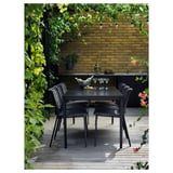 Moderno patio esterno con tavolo e sedie nere TEGELÖN, muro di mattoni, piante.