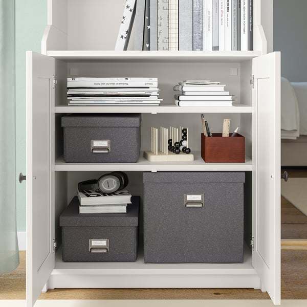 Unità di archiviazione TJOG bianca con scatole, libri e forniture per ufficio grigi.