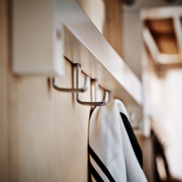 Appendiabiti in legno con ganci in metallo lucido che tengono gli oggetti. Design moderno e organizzato.