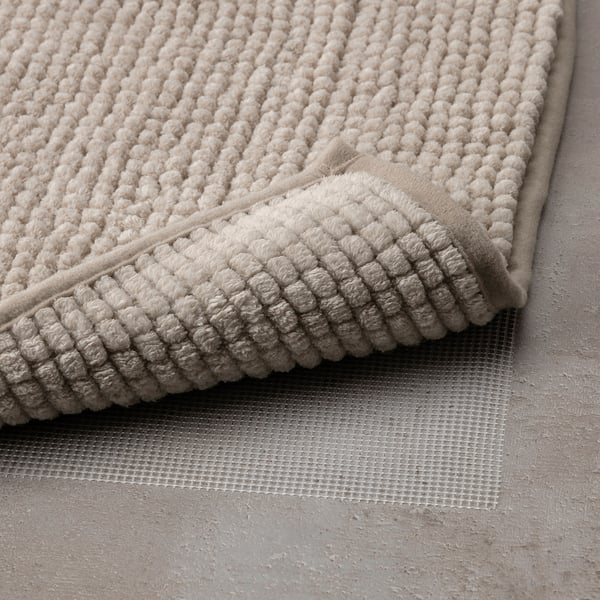 Un morbido tappetino da bagno in microfibra con una superficie ruvida e ad asciugatura rapida, piegato con un sottofondo antiscivolo visibile sotto.