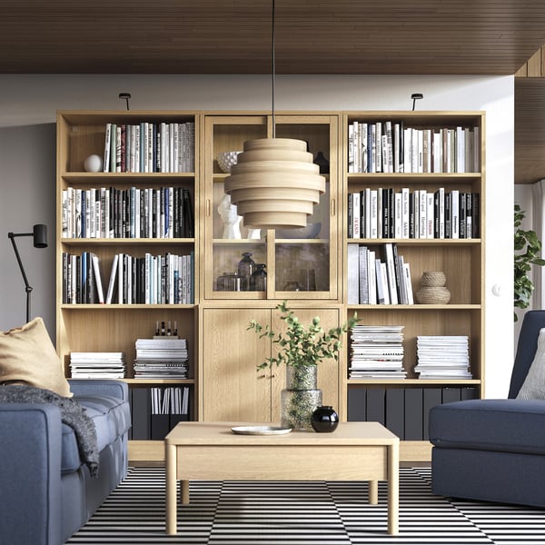 Soggiorno con mensole, libri e decorazioni TONSTAD. Mobili blu e grigi, tavolino con vassoio e pianta.