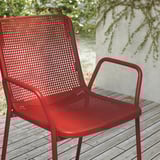 Sedia da esterno di colore rosso brillante con sedile e schienale traforati, robusta struttura in metallo, ideale per un uso durevole e a bassa manutenzione.