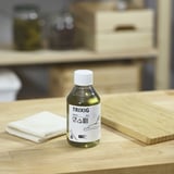 Bottiglia TRIXIG verde su tavolo di legno con tovaglia e tavola.