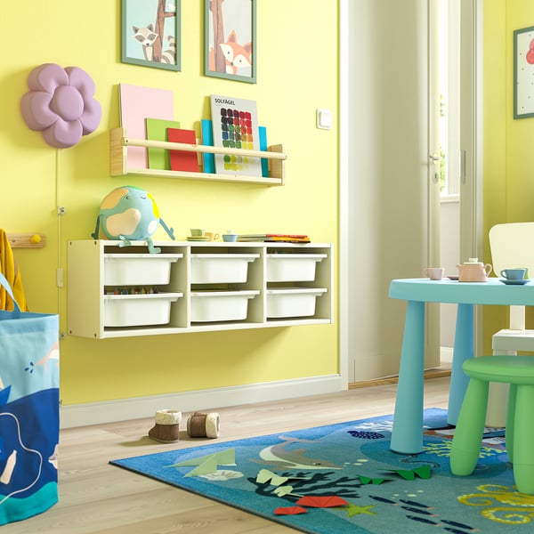 Camera dei bambini con contenitore TROFAST, giocattoli colorati, pareti verdi, pavimento in legno, dipinti, decalcomanie.