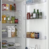 Frigorifero ben organizzato con più ripiani e scomparti, che mostra prodotti alimentari come bottiglie, barattoli e prodotti, indicando una conservazione efficiente.