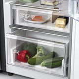 Frigo aperto con le verdure nel cassetto: broccoli, peperoni, zucchine, più pesce sul ripiano superiore.