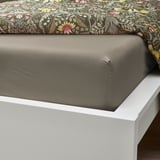 Un letto ben fatto con un lenzuolo grigio scuro su un giroletto bianco, che mostra il suo tessuto liscio e traspirante.