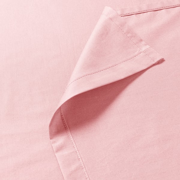 Primo piano di tessuto rosa tenue ben cucito, che mostra cuciture fini e consistenza liscia.