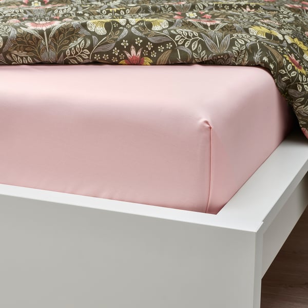 Letto con lenzuolo rosa chiaro su giroletto bianco, caratterizzato da tessuto traspirante e morbido a trama fitta.