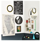 Una parete decorata con una mappa, specchi e piccole cornici. Un orologio astratto e vari oggetti sono esposti su una sporgenza.