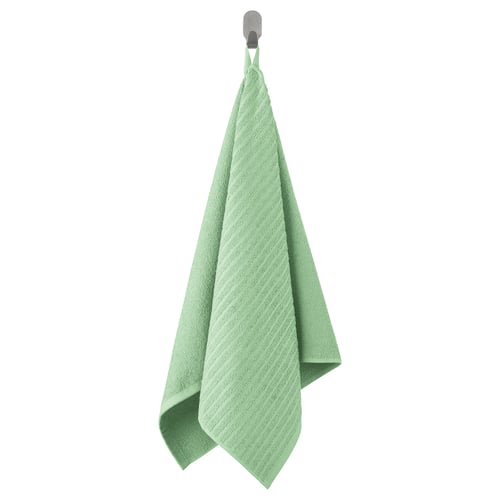 L'asciugamano VÅGSJÖN verde chiaro pende dal gancio, morbida trama in spugna, forma rettangolare, colore vivido.