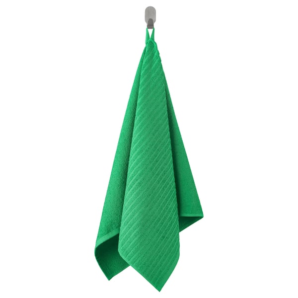 L'asciugamano VÅGSJÖN verde brillante è appeso ordinatamente a un gancio, mettendo in mostra la sua superficie morbida e strutturata e lo spessore moderato.