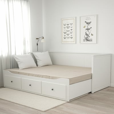 Materasso da giorno bianco con maniglie, poster naturalistici, lampada, parete grigia, pavimento in legno, tappeto beige.
