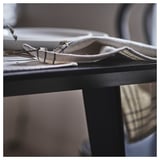 Un tovagliolo arrotolato appoggiato su un tavolo, dai toni della terra e dal design rustico in cotone e iuta.