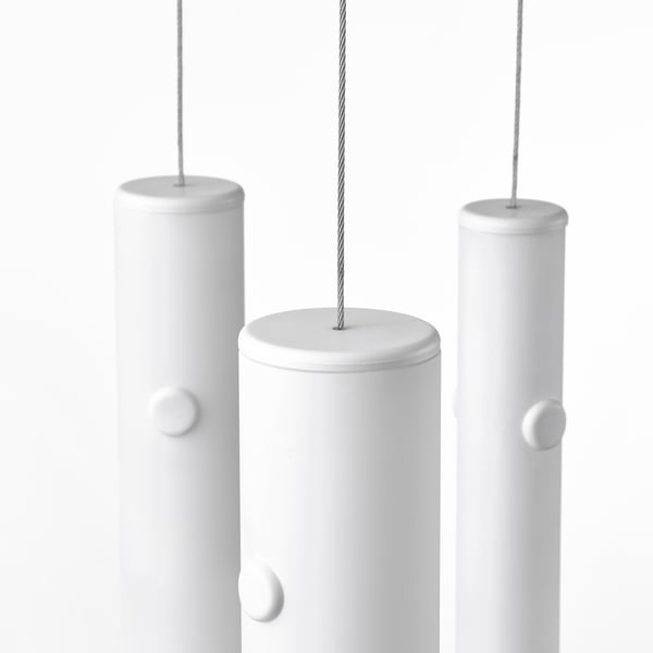 Tre moderne lampade a sospensione con diffusori in vetro smerigliato emettono una luce morbida e calda.